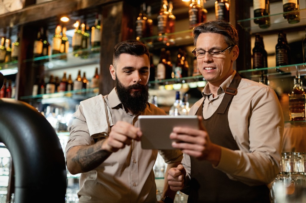 Equipo de restaurante satisfecho revisando pedidos directos en tablet